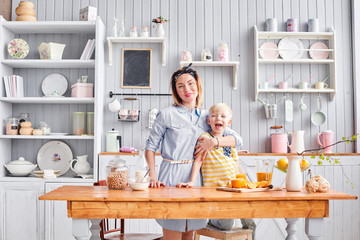 Mother and son are smiling while having a breakfast in kitchen. Bright morning in the kitchen. Healthy Breakfast cereals and fresh fruit.