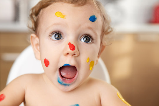 Close up portrait of funny baby with finger paint on face