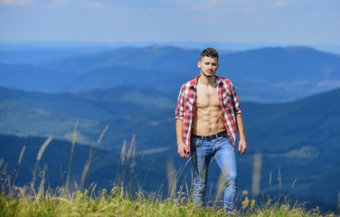 Hiker muscular torso reach mountain peak. Hiking concept. Man stand top mountain landscape background. Athlete guy relax mountains. Beautiful environment. Muscular tourist walk mountain hill