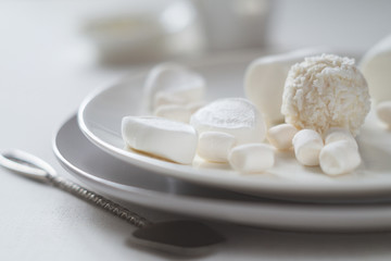 Various white candies, marshmallows and a spoon with peanut butter