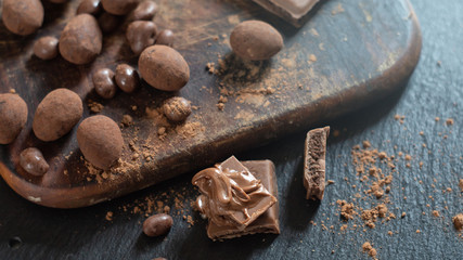Various candies and chocolate with cocoa powder on a dark wooden surface