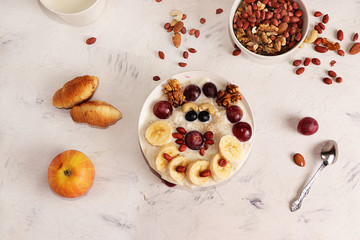 Healthy natural breakfast, funny food for children. Oatmeal with grapes,granola, nuts and honey, top view, selective focus. Healthy eating concept.
