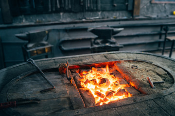 The hot furnace of the forge. Dark workshop of a blacksmith with an anvil, tools and a stove.