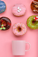 Colorful Donuts with icing and coffe cups on pastel rose background. Sweet donuts.