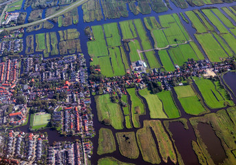 Aerial view of cultivated agricultural farming land with vivid green color as a typical dutch canals natural irrigation system shot from the air with tilt-shift focus effect