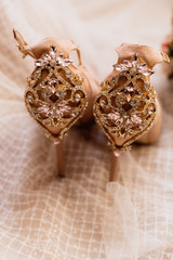 Bride's wedding shoes decorated gems stand on a part of the dress