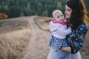 Young happy caucasian woman with little baby girl. Parent and daughter walking and having fun together. Mother playing with child outdoors. Family, parenthood, childhood, happiness concept.
