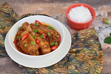 Ayam Kecap. Chicken cooked or stew in thick sweet soy sauce and spices. Garnish with scallions and sliced red chili. Served with steamed rice