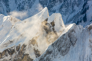 Luftaufnahme der schneebedeckten Alpen aus dem Heißluftballon mit Schneeverwehungen an den Gipfeln