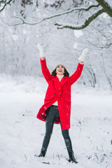 Young girl in a red coat walking in a snow-covered park. Christmas is comming. New Year. 