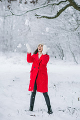 Young girl in a red coat walking in a snow-covered park. Christmas is comming. New Year. 