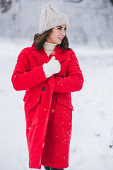 Young girl in a red coat walking in a snow-covered park. Christmas is comming. New Year. 