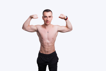 Handsome strong athletic man standing with his hands up near a white wall.