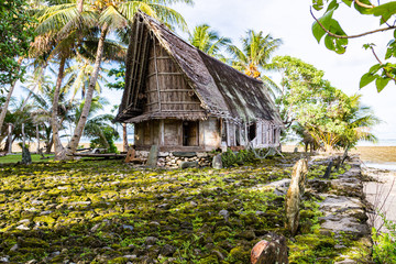 Traditional thatched yapese men's meeting house faluw or fale, a bank of megalithic stone money rai and a bunch of stone seat backs around. Shore of Pacific ocean. Yap island, Micronesia, Oceania © Dmitry
