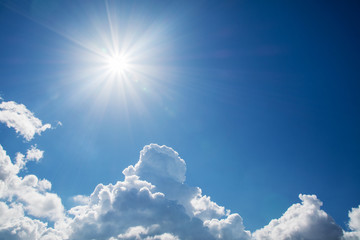Sun with rays on a background of blue sky with clouds