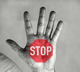 Man holds palm in front of him. He has an inscription and a stop sign on his palm. Black and white...
