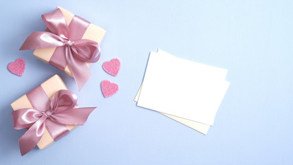 Valentine gift boxes with pink ribbon bow and romantic love letter on pastel blue background with heart shaped confetti. Valentines day banner design. Flat lay, top view.