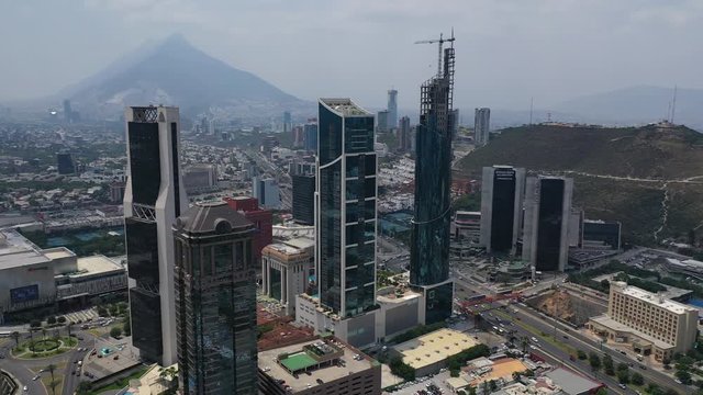 Aerial view of San Pedro Garza García Skyscrapers in Monterrey, Nuevo León, Mexico. Cityscape of modern high office buildings with mountain Cerro de la Silla in the backgrond. Drone orbiting.