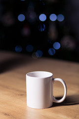 White coffee mug isolated on a wooden table on a dark background with spotlights