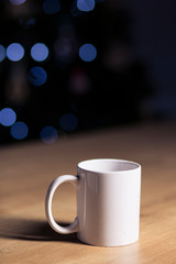 White coffee mug isolated on a wooden table on a dark background with spotlights