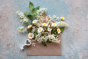 Branches with cherry flowers, key and daisies in an envelope on a colored background