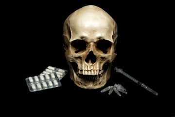 Human skull with syringre, crystals and pills on black background. Dangerous of drugs. Drugs and crime concept.