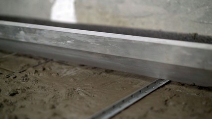 The worker levels the floors with a sinker. The construction technician is working by leveling the...