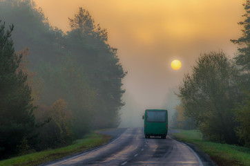 autumn morning landscape. Wet road after rain passes through the forest. The sun and trees are hidden in the fog. blur focus
