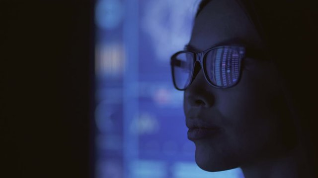 The businesswoman looking on the blue screen in the dark lab