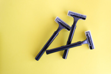 Set of disposable black razors on a yellow background