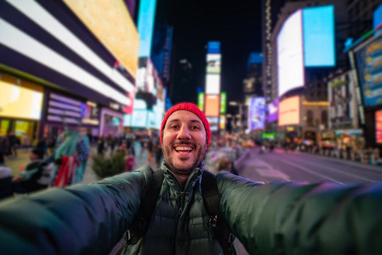 smiling young man taking a selfie with his smartphone on Times Square, New York. tourism in united states of America