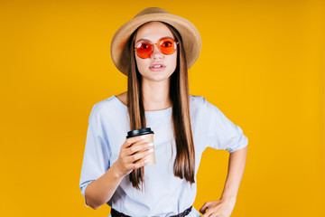 with an alarmed look through pink glasses, the girl looks at the camera holding coffee in her hand