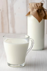 A glass bottle with kefir with bread rolls on the wooden table