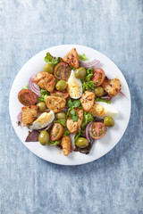 Salad with green olives, cherry tomatoes, chicken and eggs. Wooden background. Top view. 
