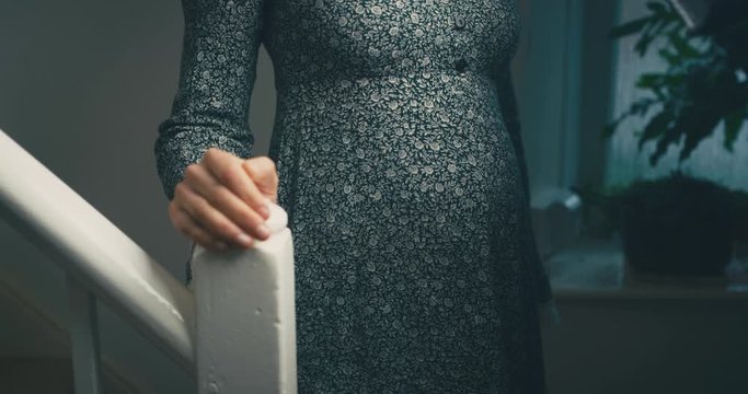 Pregnant woman standing at the bottom of stairs