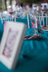 Table setting for a wedding party in pink and turquoise colors. Luxury decor. Plates, glasses, cutlery and candles. Vases with flowers.