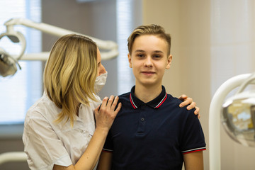 Fototapeta premium Woman dentist with a patient guy, portrait in stomatology clinic.