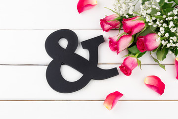 Valentine's day. Concept of love. Black wooden letter & and roses on a wooden white table background. Top view.