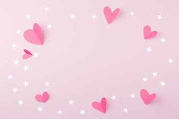Valentine's day. Concept of love. Paper hearts and confetti stars on pink background. Top view. Space for text.