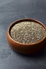 Organic raw chia seeds superfood in wooden bowl on dark stony background