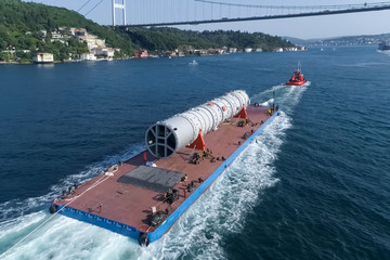 Oversized cargo transportation along the river, a distillation column on a barge floats to factory.
