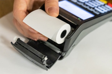 Pos terminal paper roll being replaced by a woman holding it in hand