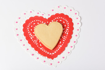Valentines Day Concept: A heart shaped sugar cookie on heart shaped doilies.