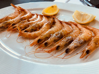 Fresh cooked shrimps with lemon on a white plate