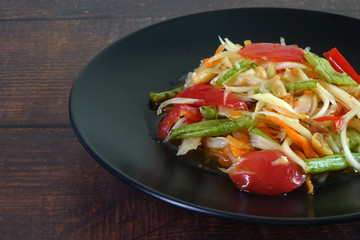 Somtam or Spicy green papaya salad, Thai cuisine. Green  papaya salad is a spicy salad made from shredded unripe papaya. Originating from ethnic Lao people, it is also eaten throughout Southeast Asia.