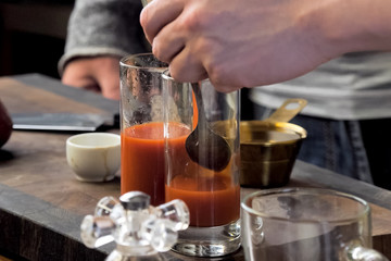 Fototapeta na wymiar Pouring tomato juice into glasses through spoon.