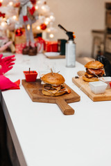 The cook is preparing a hamburger, on the background with the ingredients.  Delicious food. Menu, fast food