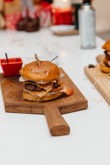 The cook is preparing a hamburger, on the background with the ingredients.  Delicious food. Menu, fast food