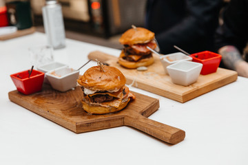 The cook is preparing a hamburger, on the background with the ingredients.  Delicious food. Menu, fast food