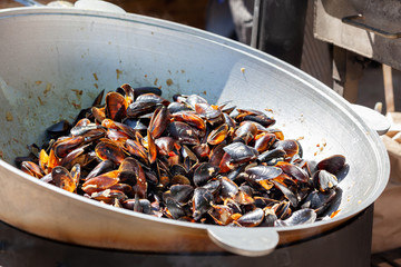 Fresh mussels at grill pan. Seafood barbecue outdoors, food festival. Picnic healthy food, mussels in shells.